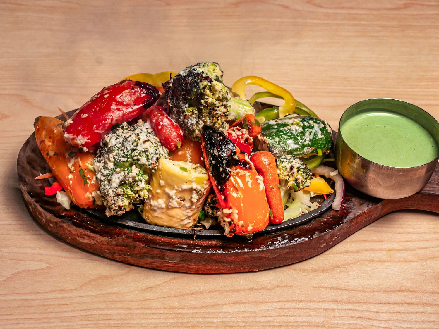 Charred broccoli, peppers, zucchini and carrot on a cast-iron sizzler with green chutney