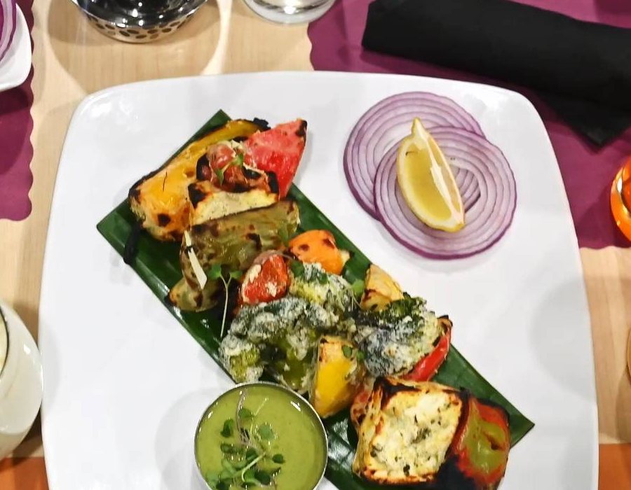Char-grilled vegetable tikka platter on banana leaf with mint chutney, onion and lemon